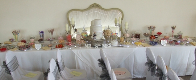 Elegant jars and dishes on a 15' long table surround the wedding cake.  The bride provided the candles and mirror.